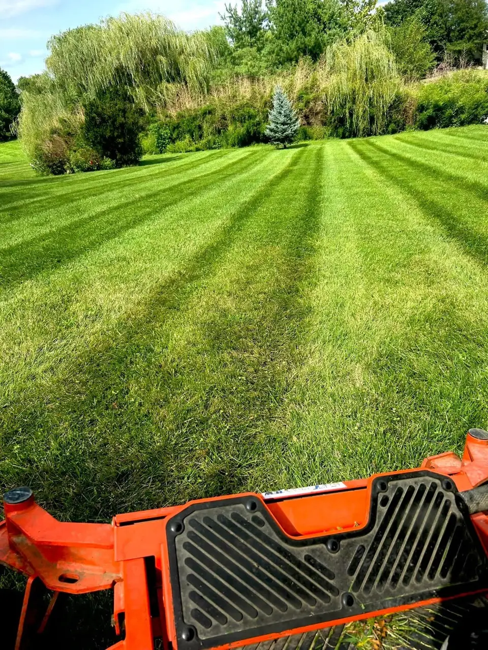 Fresh mowing stripes with a Denton Lawn Care mower in the foreground