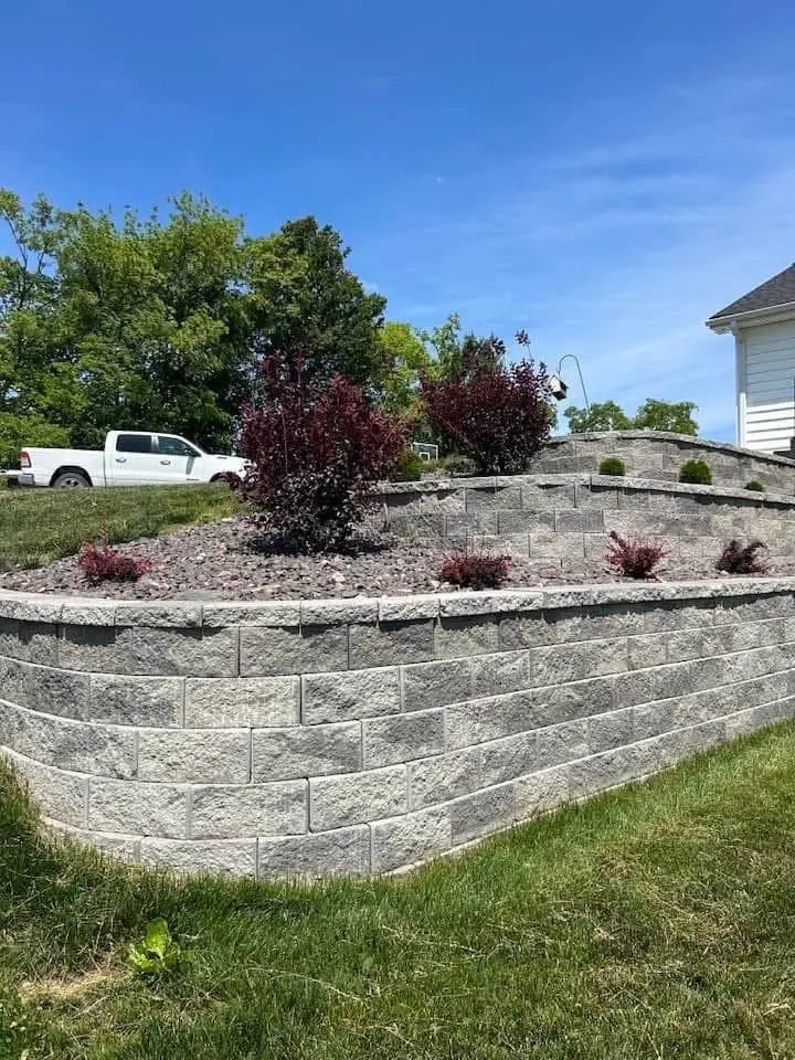 Block retaining wall with planted bed above a lawn